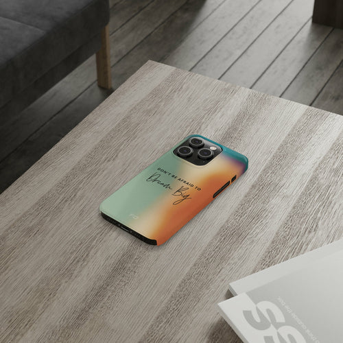 Dream Big Quote Slim Case for iPhone 14 Series displayed on a wooden table with a motivational message.