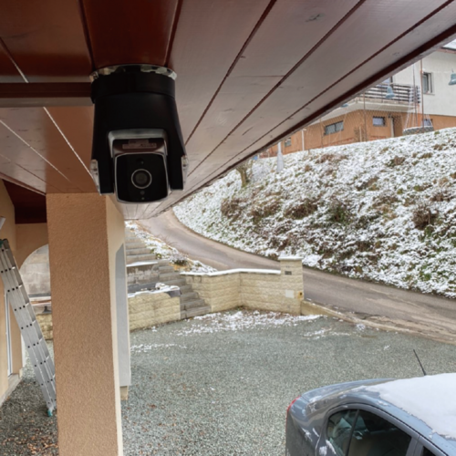 Ares Pro Outdoor Security Camera mounted under a roof, providing surveillance over a snow-covered driveway.